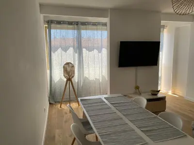 a dining room with a table and chairs and a television at Ajaccio centre bord de mer T3 in Ajaccio