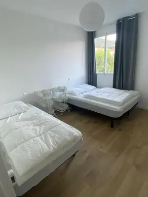 two beds in a room with a window at Ajaccio centre bord de mer T3 in Ajaccio