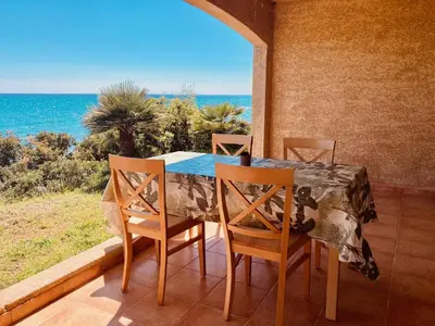 a table and chairs on a balcony with a view of the ocean at Punta di mare, appartements bord de mer in Linguizzetta