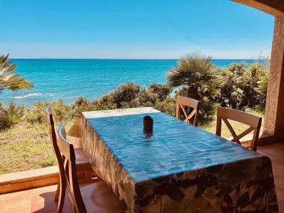 a table with chairs and a view of the ocean at Punta di mare, appartements bord de mer in Linguizzetta