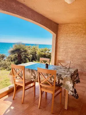 a dining room with a table and chairs and the ocean at Punta di mare, appartements bord de mer in Linguizzetta