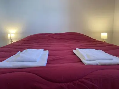 a red bed with two towels on top of it at Punta di mare, appartements bord de mer in Linguizzetta