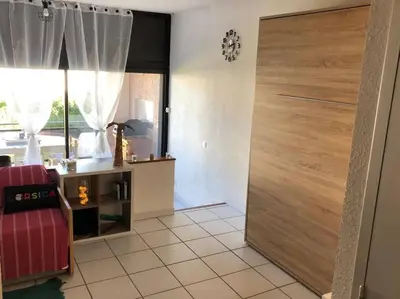 a living room with a red chair and a sliding door at 2026 - grand studio avec piscine et plage à 50 m in San-Nicolao