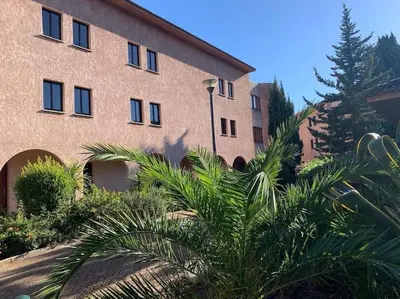 a building with a palm tree in front of it at 2026 - grand studio avec piscine et plage à 50 m in San-Nicolao