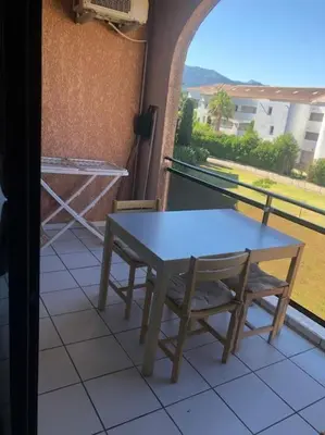 a table and chairs sitting on a balcony with a view at 2026 - grand studio avec piscine et plage à 50 m in San-Nicolao