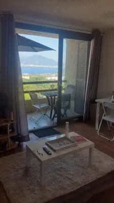 a living room with a table and a view of a patio at Charmant studio in Grosseto-Prugna