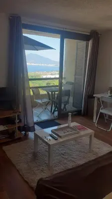 a living room with a table in front of a large window at Charmant studio in Grosseto-Prugna
