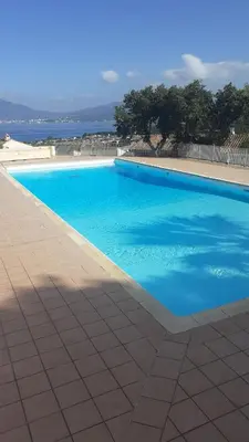 a large blue swimming pool with the ocean in the background at Charmant studio in Grosseto-Prugna