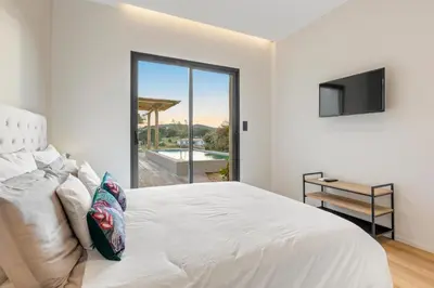 a white bedroom with a large bed and a television at Villa calme avec piscine chauffée - 6 personnes - Figari proche Porto-Vecchio et Bonifacio in Figari