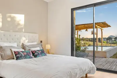 a bedroom with a white bed and a large window at Villa calme avec piscine chauffée - 6 personnes - Figari proche Porto-Vecchio et Bonifacio in Figari