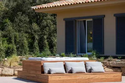 a wooden bench with a hot tub in front of a house at Villa Cargèse in Cargèse