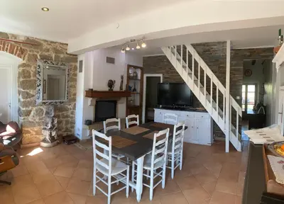 a dining room with a table and chairs and a staircase at Maison de village tout confort in Eccica-Suarella
