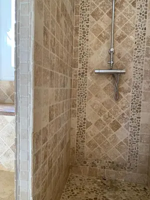 a bathroom with a shower with a stone wall at Maison de village tout confort in Eccica-Suarella
