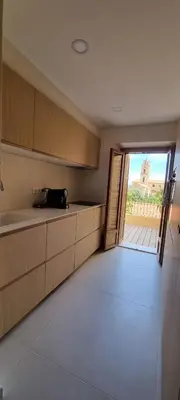 a kitchen with wooden cabinets and an open door at Appartement avec terrasse au centre du village in Cargèse