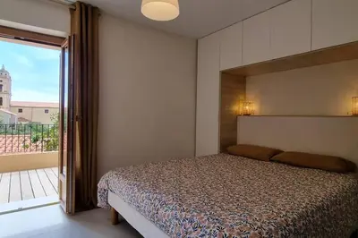 a bedroom with a bed and a large window at Appartement avec terrasse au centre du village in Cargèse