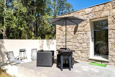 a patio with a table and an umbrella at Studio Charmant U Pinu, 2 personnes, 6 Kms de Porto Vecchio in Porto-Vecchio