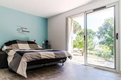 a bedroom with a bed and a large window at Studio Charmant U Pinu, 2 personnes, 6 Kms de Porto Vecchio in Porto-Vecchio