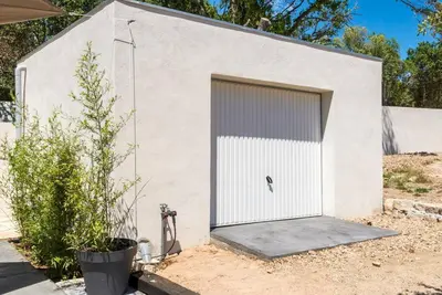a white building with a garage door on it at Studio Charmant U Pinu, 2 personnes, 6 Kms de Porto Vecchio in Porto-Vecchio