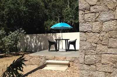 a table with a blue umbrella and two chairs at Studio Charmant U Pinu, 2 personnes, 6 Kms de Porto Vecchio in Porto-Vecchio