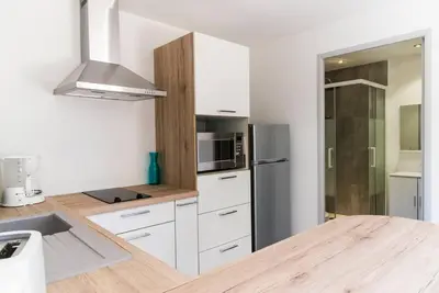 a kitchen with white cabinets and a stainless steel refrigerator at Studio Charmant U Pinu, 2 personnes, 6 Kms de Porto Vecchio in Porto-Vecchio