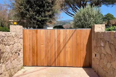 a wooden fence in front of a stone wall at Studio Charmant U Pinu, 2 personnes, 6 Kms de Porto Vecchio in Porto-Vecchio