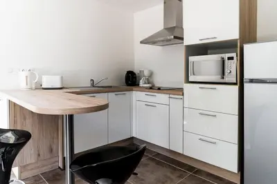 a kitchen with white cabinets and a black chair at Studio Charmant U Pinu, 2 personnes, 6 Kms de Porto Vecchio in Porto-Vecchio