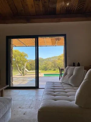 a living room with a couch in front of a sliding glass door at Villa de charme avec piscine in Sotta