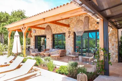 a patio with chairs and tables and a brick wall at Casa Nessa Di Pinarello in Sainte-Lucie de Porto-Vecchio