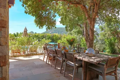 a table and chairs on a patio with a tree at Casa Nessa Di Pinarello in Sainte-Lucie de Porto-Vecchio