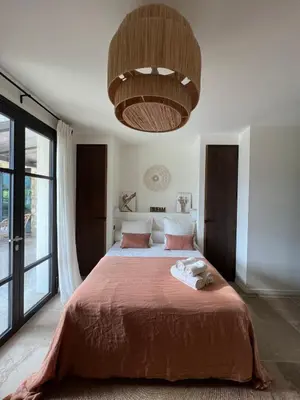 a bedroom with a large bed and a large chandelier at Casa Nessa Di Pinarello in Sainte-Lucie de Porto-Vecchio