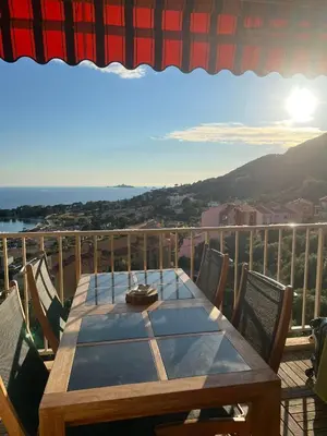 a wooden table on a balcony with a view of the ocean at Super appartement vue Sanguinaires in Ajaccio