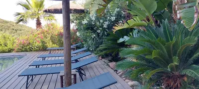three blue benches sitting on a deck next to a pool at La baie des anges in Porto-Vecchio