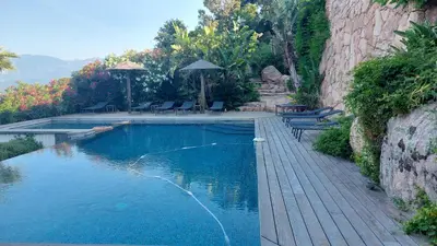 a swimming pool with chairs and umbrellas next to at La baie des anges in Porto-Vecchio