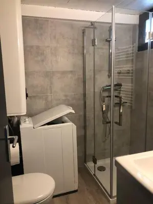 a bathroom with a glass shower and a toilet at Duplex au Village in Tox