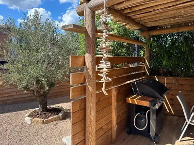 a wooden pergola with a tv and a tree at T3 avec spa, hyper centre, port in Porto-Vecchio