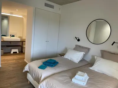 two beds in a room with a mirror and a bathroom at A1 Magnifique appt 6 personnes Lofts de Ste Lucie in Zonza