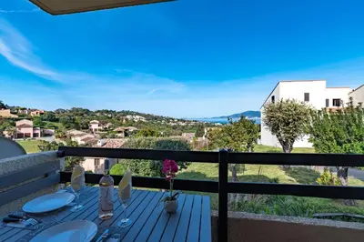 a table on the balcony of a house with a view at Kallistea - Appartement avec vue mer in Porticcio
