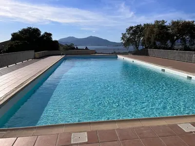 a large blue swimming pool with a view of the water at Kallistea - Appartement avec vue mer in Porticcio
