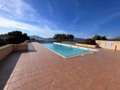 a swimming pool on a brick patio with a blue sky at Kallistea - Appartement avec vue mer in Porticcio