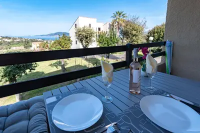 a table with glasses and a bottle of wine on a balcony at Kallistea - Appartement avec vue mer in Porticcio