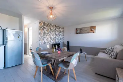 a kitchen and living room with a table and a refrigerator at Kallistea - Appartement avec vue mer in Porticcio