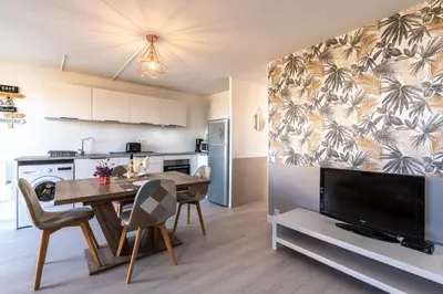 a kitchen and dining room with a table and a television at Kallistea - Appartement avec vue mer in Porticcio