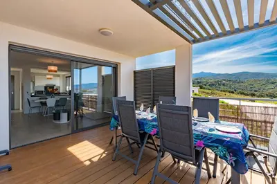 a dining room with a table and chairs on a balcony at Nepita in Porticcio