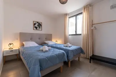 a bedroom with a bed with blue sheets and a window at Nepita in Porticcio