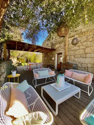 a patio with wicker chairs and tables on a wooden deck at Les Bergeries de Figari in Figari