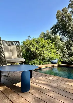 a chair and a table on a deck next to a pool at Les Bergeries de Figari in Figari