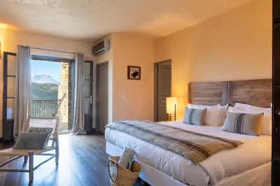 a bedroom with a large bed and a balcony at Hôtel Case Latine in Lama