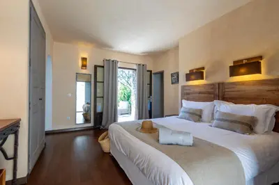 a bedroom with a large white bed with a wooden headboard at Hôtel Case Latine in Lama