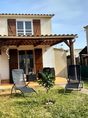 two chairs sitting in the grass in front of a house at Villa, maison bord de mer climatisée in Poggio-Mezzana