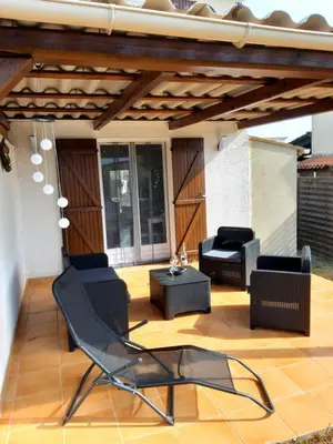 a patio with a black chair and a table at Villa, maison bord de mer climatisée in Poggio-Mezzana